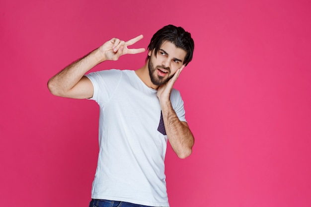 Photo gratuite homme en chemise blanche faisant signe de la main de la paix et envoi de message.