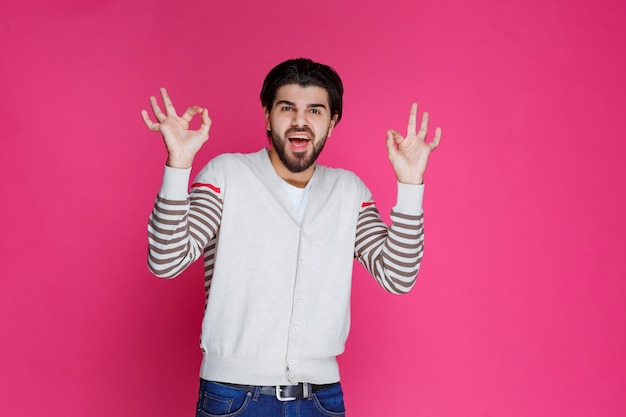 Homme en chemise blanche faisant signe de la main pleine satisfaction ou méditation.