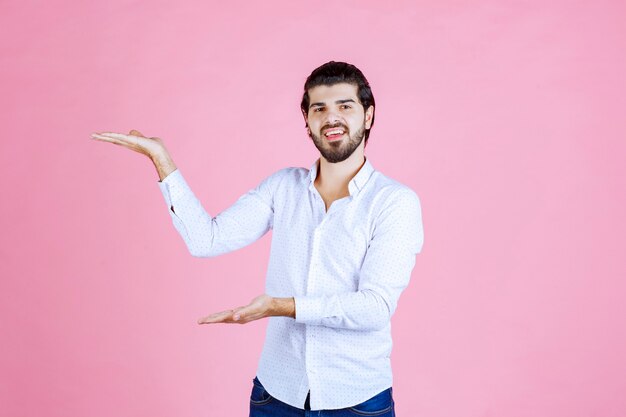 Homme en chemise blanche montrant le côté gauche avec émotions.