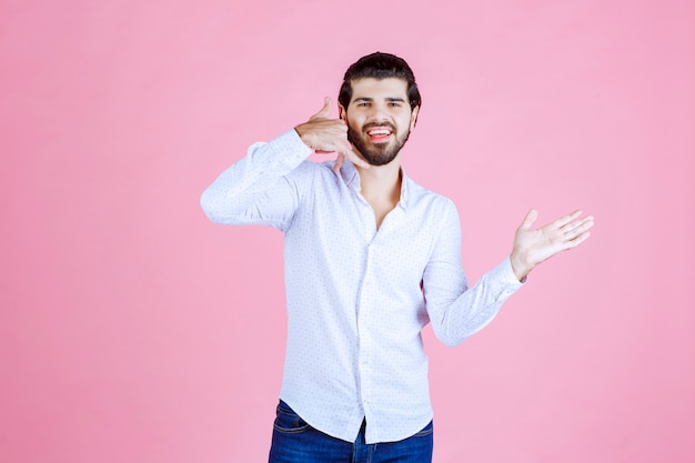 Homme en chemise blanche montrant l'indicatif d'appel.