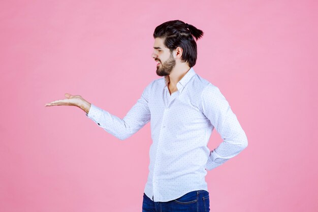 Homme en chemise blanche montrant quelque chose dans sa main.