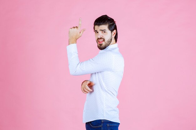 Homme en chemise blanche montrant ses muscles et sa puissance.