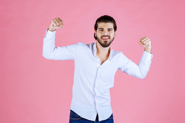 Homme en chemise blanche montrant ses muscles et sa puissance.