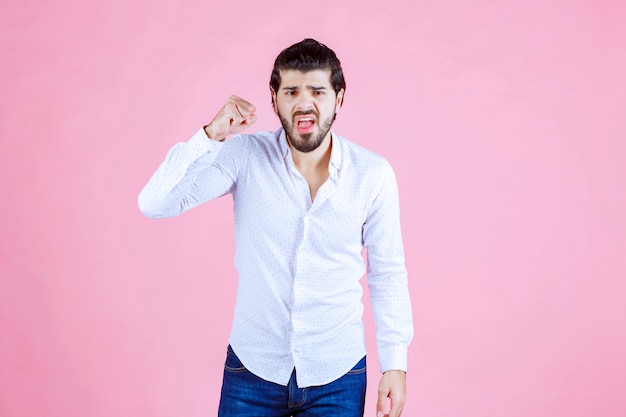 Homme en chemise blanche montrant ses muscles et sa puissance.