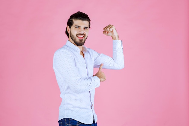 Homme en chemise blanche montrant ses poings puissants.