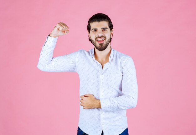 Homme en chemise blanche montrant ses poings puissants.