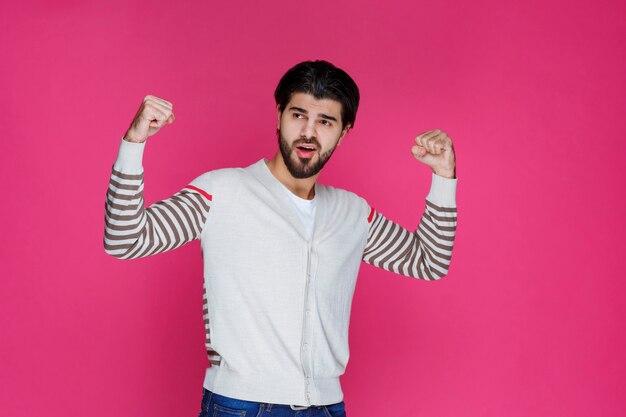 Homme en chemise blanche montrant ses poings et sa puissance.