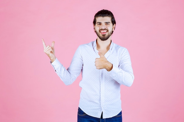 Homme en chemise blanche montrant un signe positif de la main.