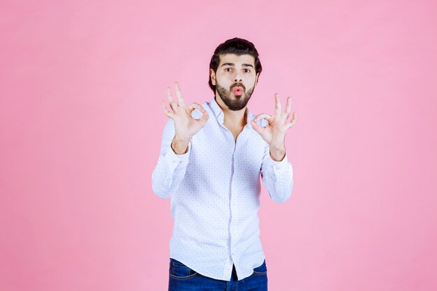 Homme en chemise blanche montrant un signe positif de la main.