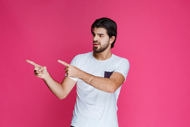 Homme en chemise blanche pointant et présentant quelque chose sur le côté gauche.