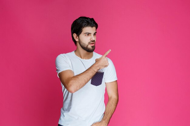 Homme en chemise blanche pointant et présentant quelque chose dans le côté droit.