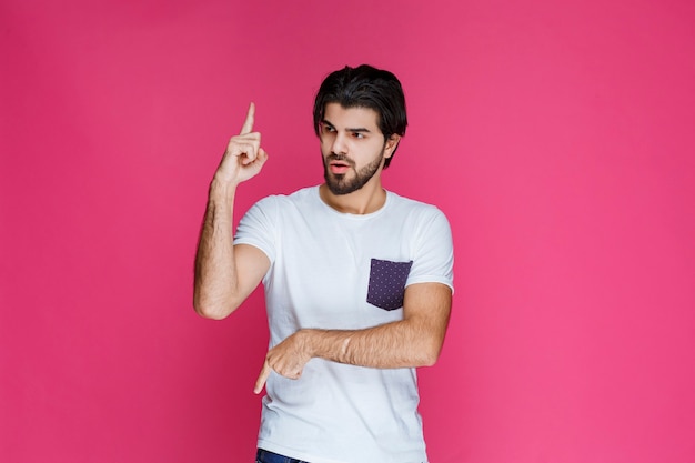 Homme en chemise blanche pointant vers quelque chose avec son doigt pointé.