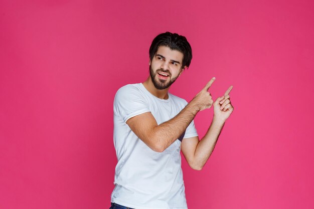 Homme en chemise blanche pointant vers quelque part et présentant quelqu'un ou montrant simplement la direction.