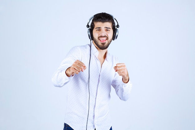 Homme en chemise blanche portant des écouteurs et profitant de la musique