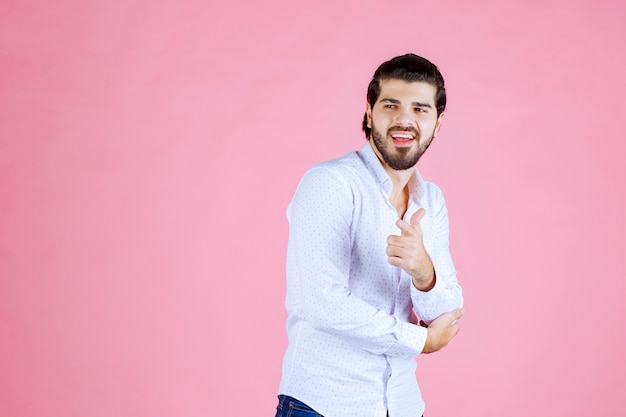 Homme en chemise blanche remarquant et pointant du doigt la personne devant.