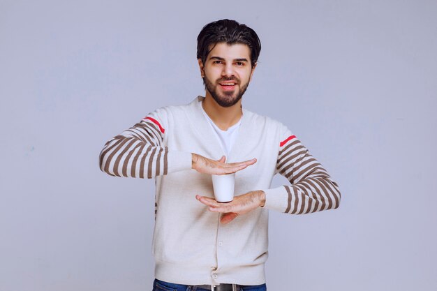 Homme en chemise blanche tenant et prenant une tasse de café.