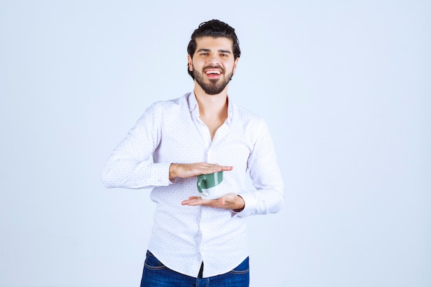 Homme en chemise blanche tenant une tasse de café et en profitant