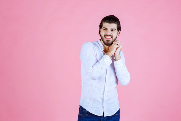 Homme en chemise blanche unissant les mains et priant.