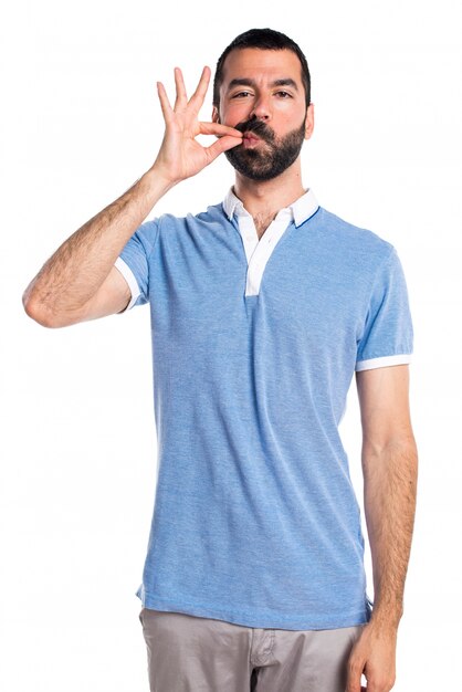 Homme avec une chemise bleue faisant un geste de silence