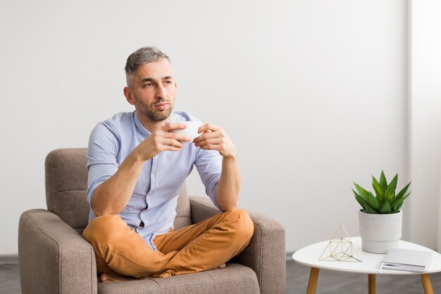 Homme en chemise bleue tenant une tasse blanche