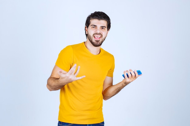 Homme en chemise jaune pointant son smartphone et en profitant.