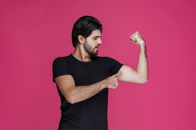 Homme en chemise noire montrant ses muscles du bras