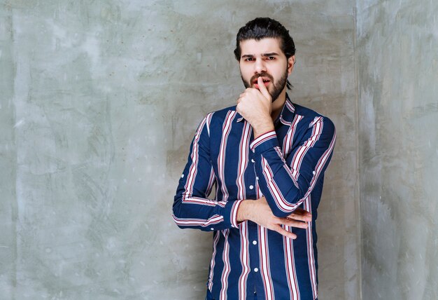 L'homme en chemise rayée a l'air confus et réfléchi.