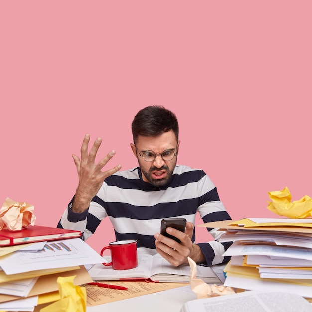 Photo gratuite homme en chemise rayée assis au bureau avec des documents