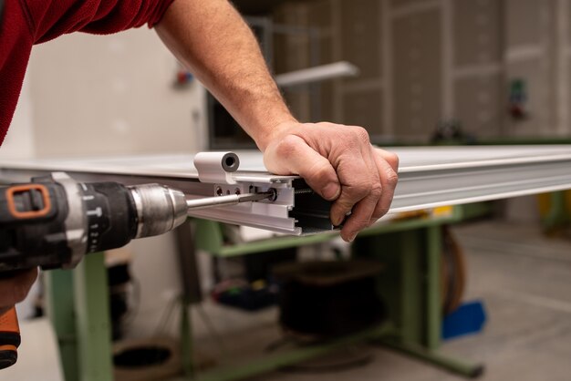 Homme avec une chemise rouge faisant une fenêtre avec des outils industriels