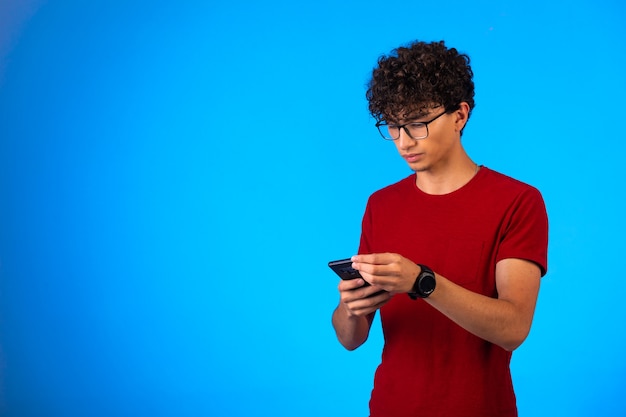 Homme en chemise rouge prenant selfie ou passant un appel téléphonique et utilise le clavier à écran tactile.