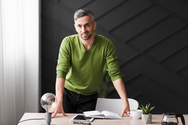 Photo gratuite homme en chemise verte, debout derrière un bureau