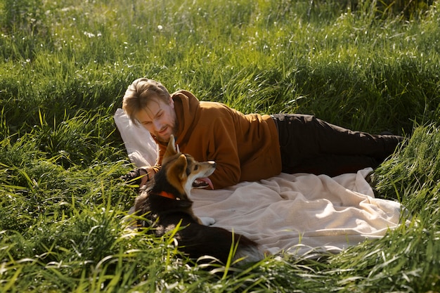 Photo gratuite homme avec chien sur couverture à l'extérieur plein coup