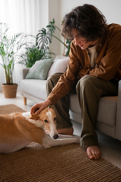 Photo gratuite homme avec chien lévrier à la maison sur le canapé