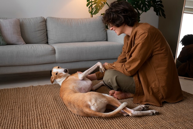 Photo gratuite homme avec chien lévrier à la maison sur le canapé