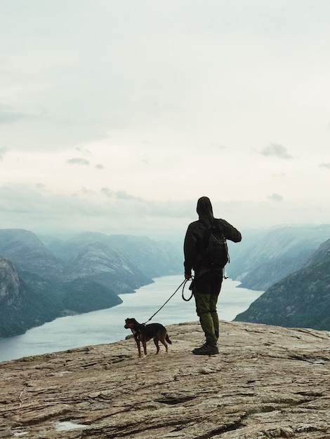 L&#39;homme avec un chien se tient devant un beau paysage