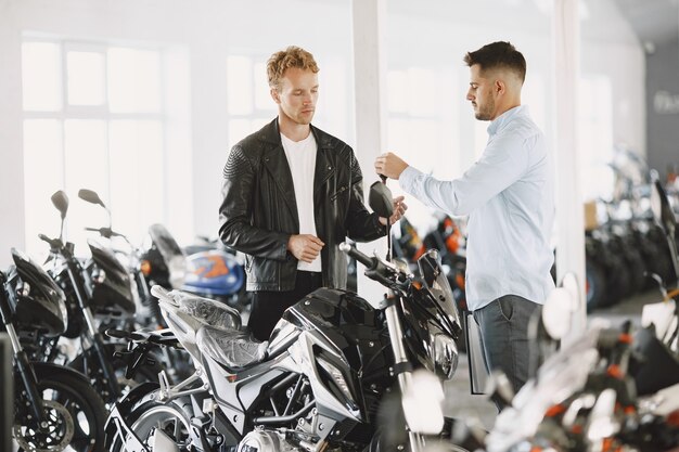 L'homme a choisi des motos dans un magasin de moto. Guy dans une veste noire. Gestionnaire avec client.