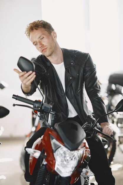 L'homme a choisi des motos dans un magasin de moto. Guy dans une veste noire.