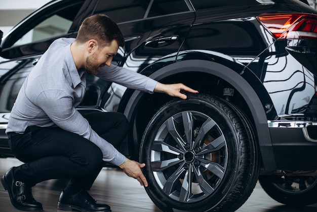 Homme choisissant une voiture et vérifiant les pneus