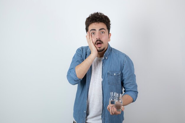 homme choqué tenant un verre d'eau sur blanc.