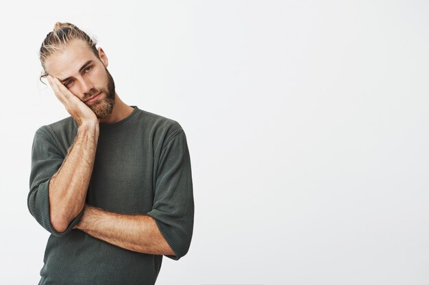 homme avec coiffure élégante et barbe tenant la tête avec la main étant fatigué