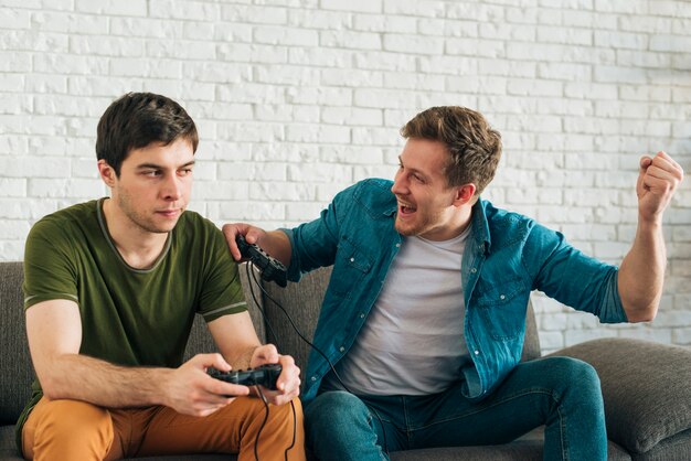 Homme en colère regardant l&#39;homme applaudir après avoir remporté le jeu vidéo