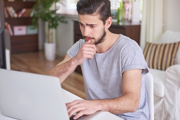 Homme confus assis devant son ordinateur