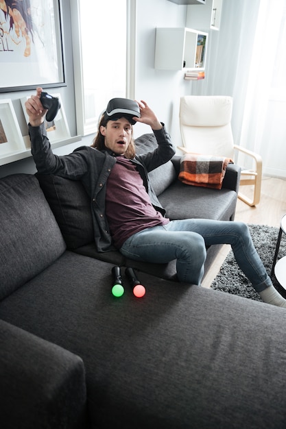 Homme confus assis à la maison jouer à des jeux avec des lunettes 3d