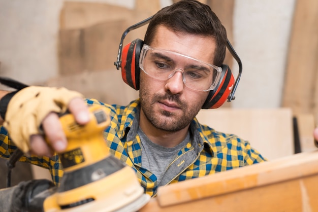 Homme Constructeur Charpentier Polit Planche De Bois Avec Une Ponceuse D'orbite Aléatoire