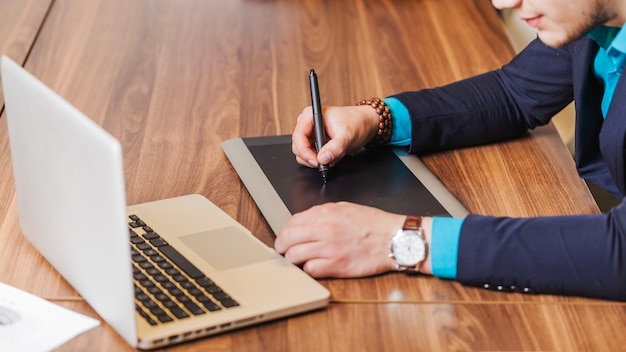 Photo gratuite homme en costume assis au dessin de bureau