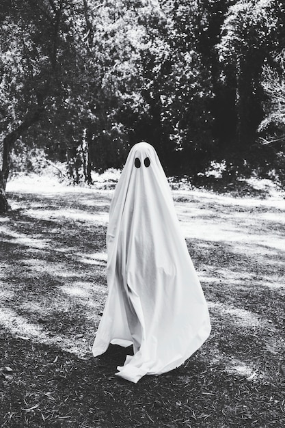 Homme en costume de fantôme debout dans la forêt