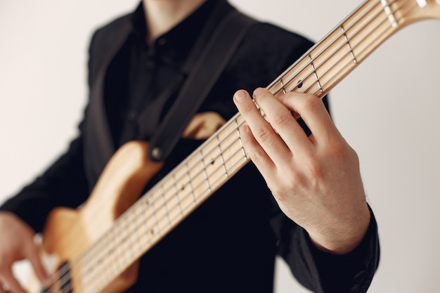 Homme en costume noir debout avec une guitare