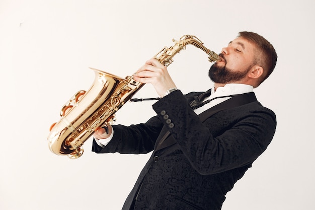 Homme en costume noir debout avec un saxophone