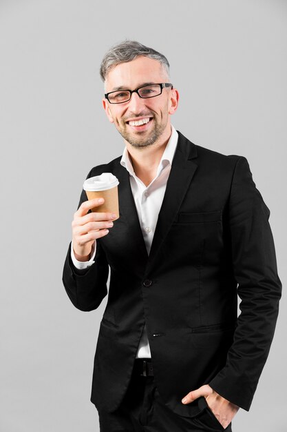 Homme en costume noir portant une tasse en plastique