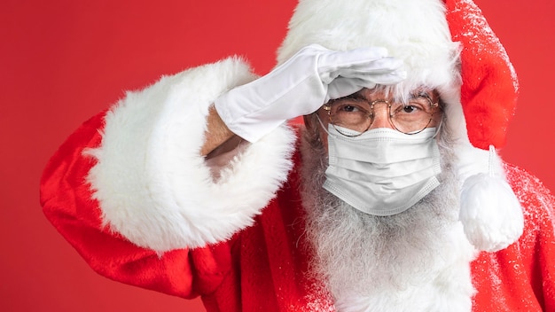 Homme en costume de père Noël portant un masque médical